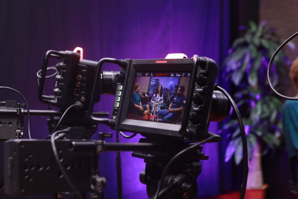Cinema camera with an attached monitor showing a lit interview set