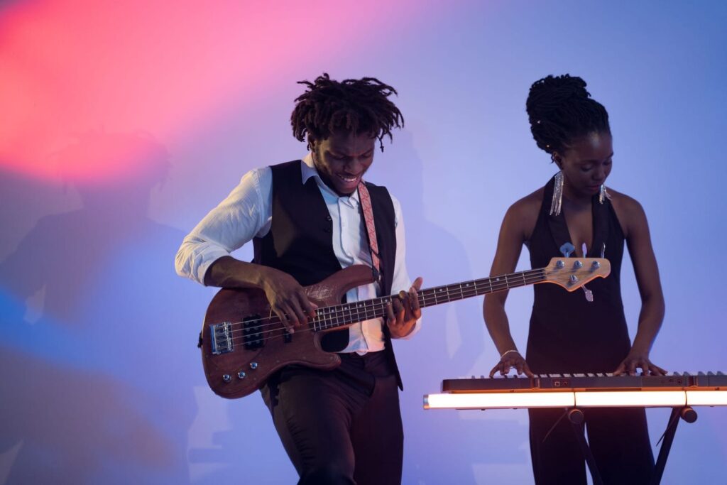 Bass player and keyboardist performing on a colorfully lit studio set