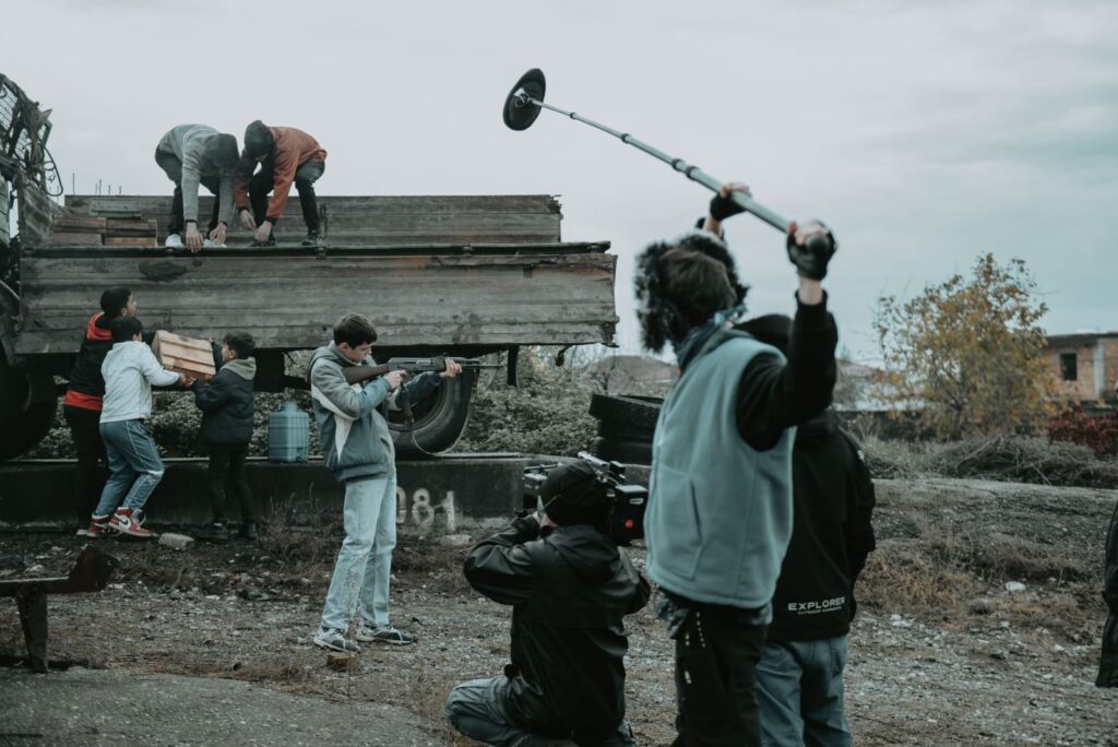 Film crew shooting outdoors with a sound operator holding a boom microphone