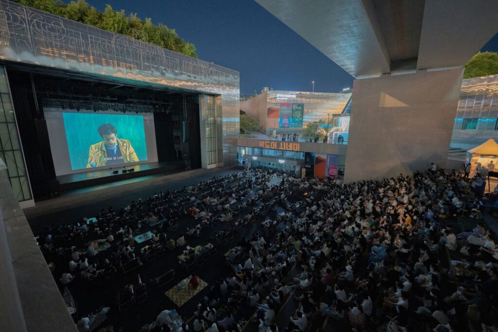 Large audience watching an outdoor film screening at night